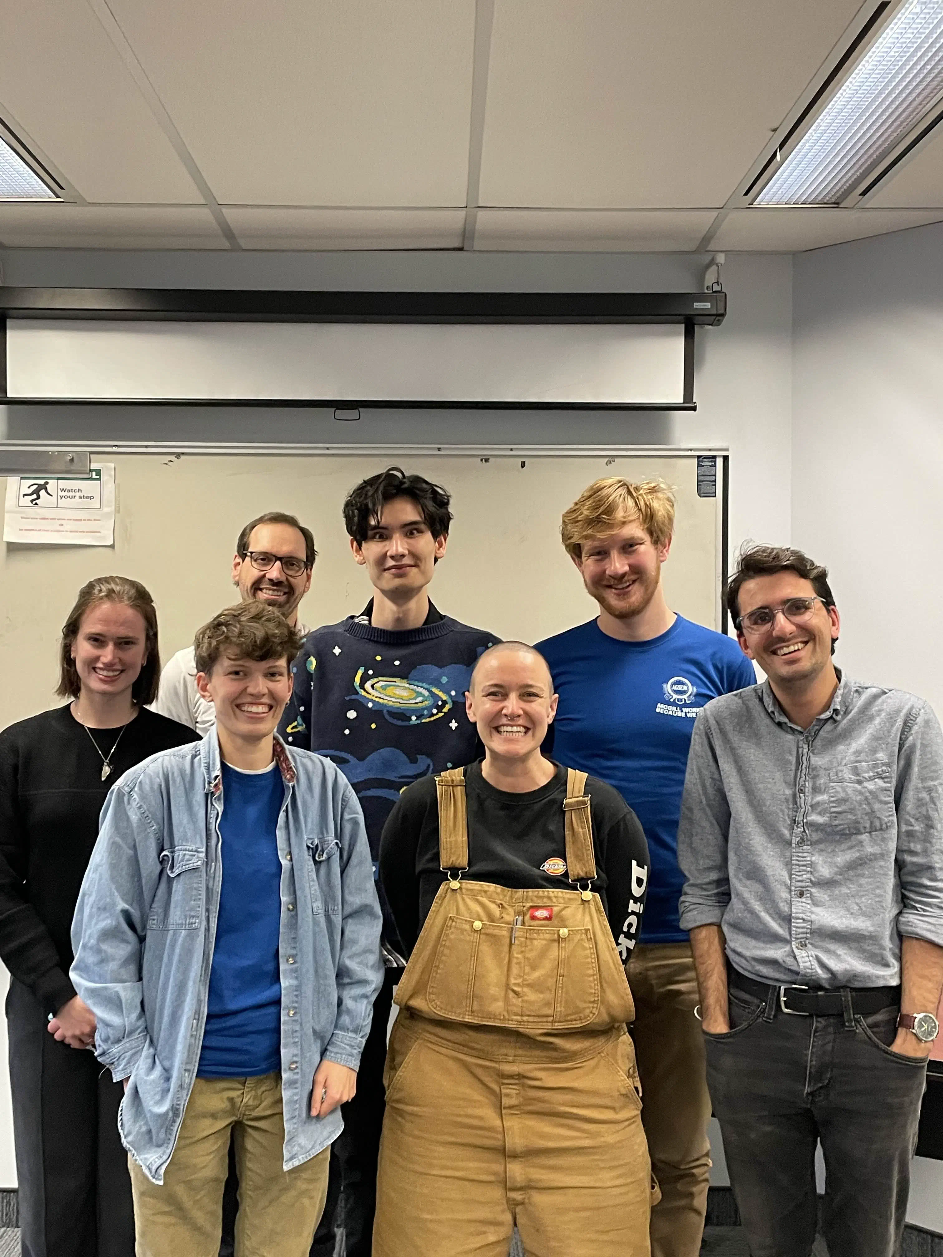 Members of your November 7th bargaining team, post-bargaining. a group of seven people in a classroom, smiling at the camera.